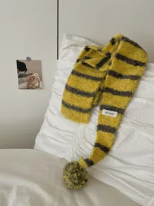 Detail view of the cozy yellow and grey striped knitted scarf with cute pom-pom accessory.