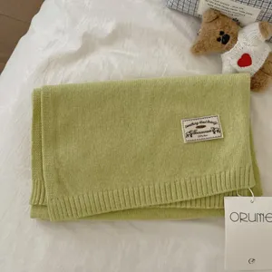 Solid color knitted wool scarf for women, soft warm winter accessory with label detail.