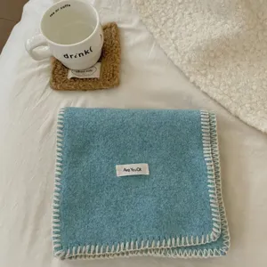 Bufanda de invierno de punto acogedor en azul liso con bordes cosidos blancos y etiqueta.