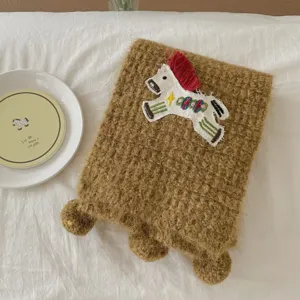 Brown knitted scarf with cute horse embroidery and pom poms, cozy winter fashion accessory.