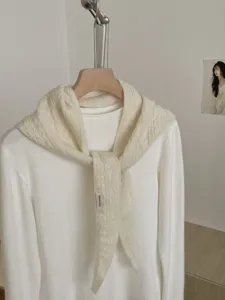 Detailansicht des cremefarbenen Strickpullovers und Schals, weiche Wolle, minimalistisch.