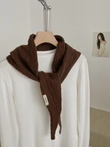 Detailaufnahme eines braunen Strick-Dreieckschals mit Wolltextur für Herbst und Winter.