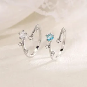 Primo piano dettagliato di anelli aperti asimmetrici a stella con zirconi scintillanti in argento.