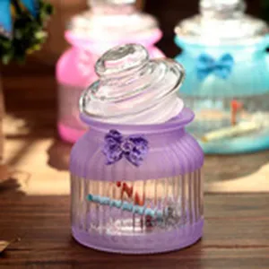 Glass wish bottle with bow decoration, transparent purple container with lid for gifts.