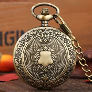 Vintage bronze pocket watch detail shot with embossed shield carving on rustic wood.