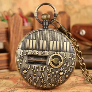 Detailed closeup of vintage bronze pocket watch with piano keys and musical notes relief design.