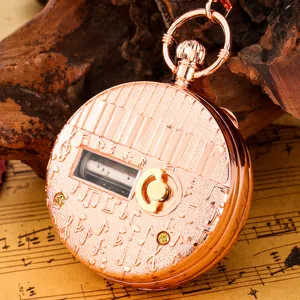 Close-up detail of vintage rose gold music box pocket watch with piano keys and musical notes.