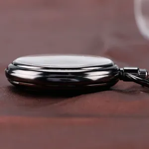 Detail view of a classic black mechanical pocket watch, showing its sleek side profile.