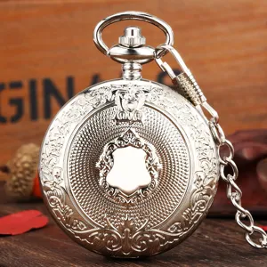 Detailed view of vintage silver pocket watch with intricate carved shield and metal chain.
