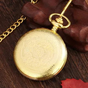 Vintage gold pocket watch detail view, elegant floral engraved pattern and metal chain close up.