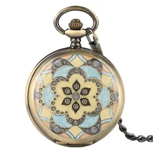 Vintage bronze pocket watch detail showing intricate floral enameled dial design and chain.