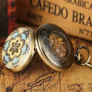 Close-up detail of vintage bronze mechanical pocket watch with green enamel flower design.