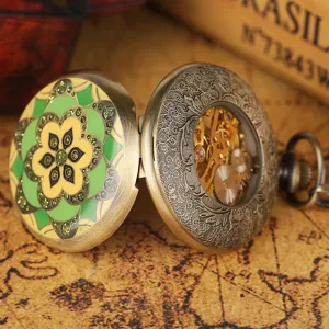 Vintage bronze manual mechanical pocket watch with green enamel flower and visible gears.