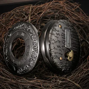 Vintage music pocket watch detail shot, black metal case with Roman numerals and notes.