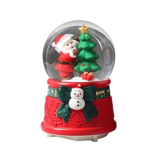 Christmas snow globe music box with Santa Claus and tree, festive desktop decoration.