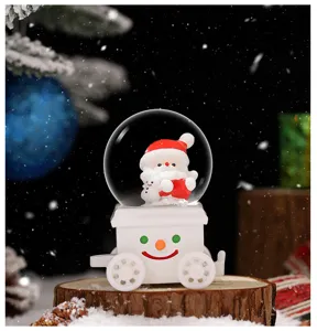 Nahaufnahme einer niedlichen Weihnachtsschneekugel mit Weihnachtsmann auf weißer Zugbasis.