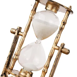 Vintage European style hourglass timer with white sand and gold retro metal frame ornament.