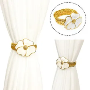 Vista dettagliata fermatenda floreale oro e bianco, elegante clip a molla per tende.