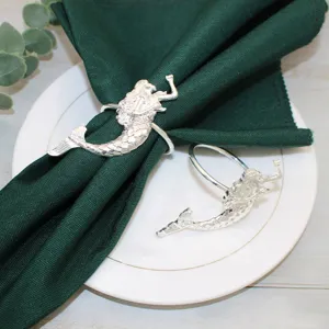 Primo piano di portatovaglioli sirena argento su panno verde e piatto bianco decorato.