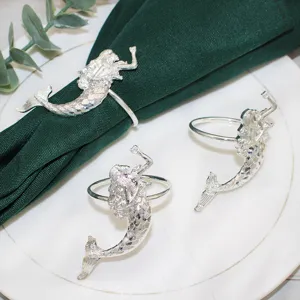 Portatovaglioli a sirena argento su tovagliolo verde e piatto bianco per decorazione tavola.