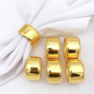 Set of shiny gold metal napkin rings with white napkin for elegant table decor settings.