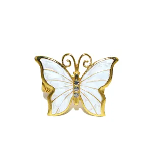 Dettaglio fibbia per tende a farfalla in metallo dorato con ali bianche e strass brillanti.
