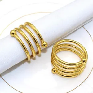 Gold metal napkin rings set, spiral design napkin holders for wedding dining table decor detail.