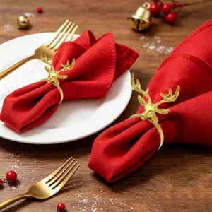 Close-up of golden reindeer napkin ring with red fabric on wooden table for holiday decor.