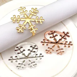 Close-up view of three metallic snowflake napkin rings in gold, silver, and rose gold finishes.