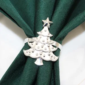 Close-up detail of a shiny silver Christmas tree napkin ring holding a dark green cloth.