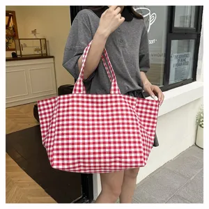 Λεπτομερής άποψη της casual τσάντας tote από καμβά με κόκκινα και λευκά καρό σε καθημερινό στιλ.