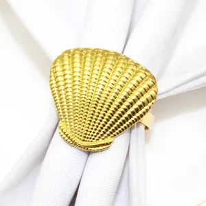 Close-up detail of a shiny gold shell napkin ring holding a clean white cloth napkin.