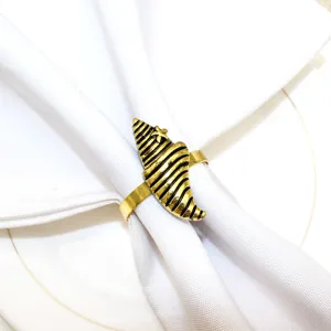 Detailed view of gold metal seashell napkin ring for coastal theme table decoration.