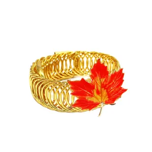 Detailaufnahme des goldenen Feder-Vorhanghalters verziert mit einem orangen Ahornblatt.
