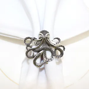 Detailed close up of a vintage silver metal octopus napkin ring on white table cloth.