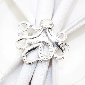 Detailed closeup of a silver octopus napkin ring holding a white napkin, elegant ocean themed decor.