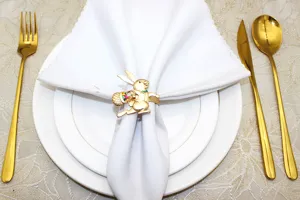 Portatovaglioli con coniglietto di Pasqua dorato e uova colorate, elegante decoro tavola.