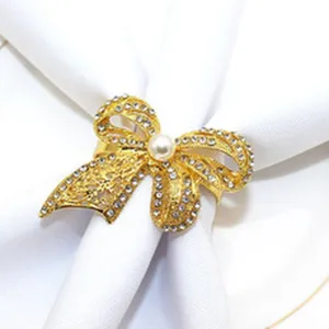Elegant gold rhinestone bow napkin ring with faux pearl, perfect for table decor.