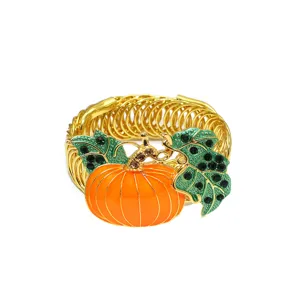 Detail view of a golden spring curtain tieback featuring an orange enamel pumpkin and crystal leaves.