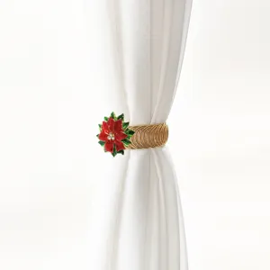 Detail shot of a golden spring curtain tieback with a vibrant red poinsettia flower decoration.