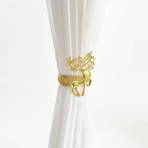 Dettaglio fermatenda cervo in metallo dorato, accessorio decorativo minimalista per interni.