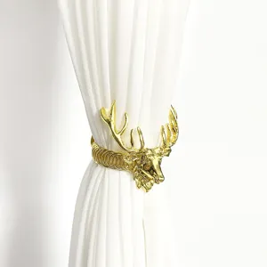 Nahaufnahme eines goldenen Hirschkopf Metall Vorhanghalters, elegante Heimdeko Raffhalter.