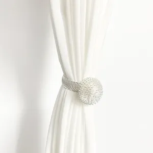 Close-up detail of silver metal wire curtain tieback with decorative ball design.