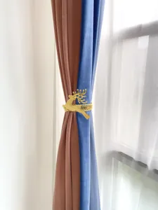 Detailaufnahme des goldenen Hirsch Vorhanghalters mit edler Federbindung an Samtvorhängen.