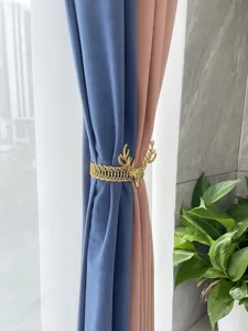 Detailed shot of gold metal deer head curtain tieback buckle holding blue and pink drapes.