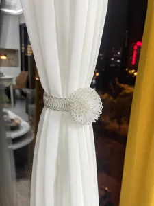 Detailed view of silver metal curtain tieback, handmade wire flower spring decorative buckle.