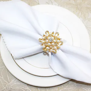 Detailed view of the elegant gold pearl rhinestone napkin ring on a white cloth and plate.