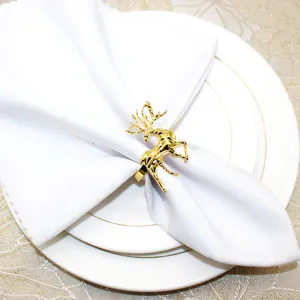 Close up of gold metallic deer napkin ring on white napkin and plates, elegant holiday table decor.