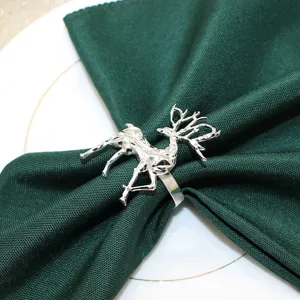 Silver geometric reindeer napkin ring with dark green cloth napkin for holiday table decor.