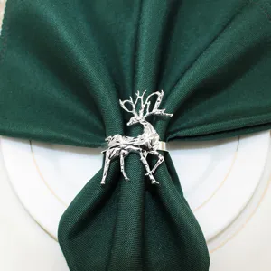 Silver metal geometric reindeer napkin ring with dark green cloth napkin for holiday decor.